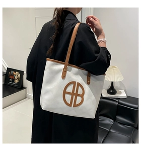Detailed view of the large white contrast tote bag worn over the shoulder by a model