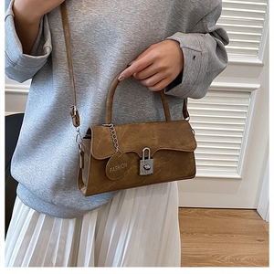 Detail of vintage brown leather crossbody bag with silver lock and decorative hangtag