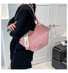 Close-up of pink woven tote bag with leather straps and decorative fashion ribbon detail