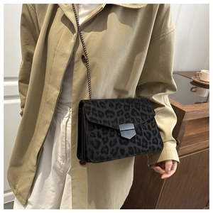 Detail of leopard print bag with silver chain strap worn over a beige coat