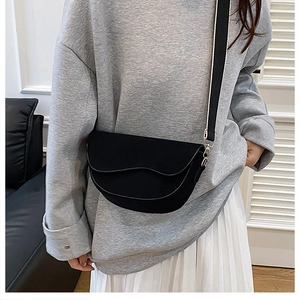 Vue détaillée du sac besace noir mat avec rabat ondulé et large bandoulière bicolore