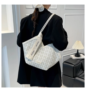 Detailed back view of a beige tweed tote bag with letter-printed straps on a model