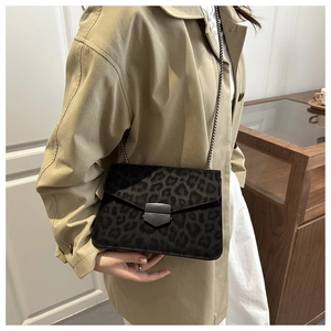 Detail of leopard print chain bag featuring dark grey metal buckle on a khaki trench coat