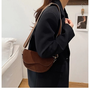 Détail d'un sac besace marron foncé mat avec une large bandoulière en tissu rayé