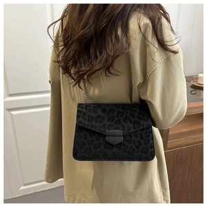 Detail of a vintage leopard print crossbody bag with sleek black metal buckle and chain