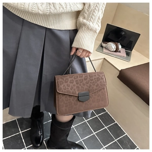 Brown leopard print chain bag styled with a white cable knit sweater and pleated skirt