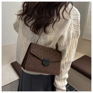 Detail of leopard print crossbody bag with metal chain strap and sleek metal clasp closure