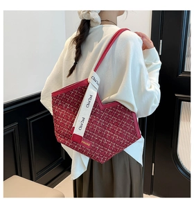 Detail of red tweed tote bag with printed canvas strap and metallic fashion emblem