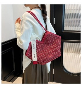 Detail view of red tweed tote bag with V-shaped opening and white handles on model