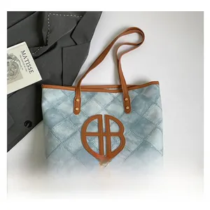 Close-up of quilted denim tote bag featuring large brown leather BB logo and gold studs