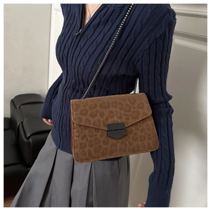 Detail of leopard print crossbody bag with black chain strap on a model outfit