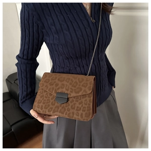 Close-up of leopard print crossbody bag with metallic chain and buckle on model