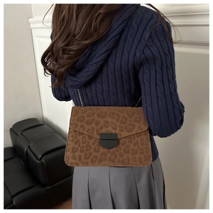 Detail of leopard print flap bag with metal chain strap and shield lock on a model