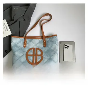 Flat lay of denim tote bag with leather handles alongside office essentials and lifestyle items
