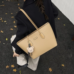 Large beige woven embossed tote bag with teddy bear pendant and shoulder strap