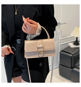 Detailed view of beige leather satchel featuring a premium gold D-ring buckle and handle
