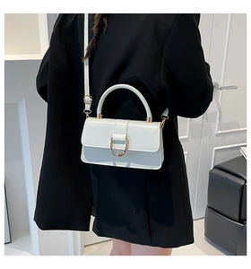 Close-up of white leather handbag with golden D-ring buckle and elegant top handle
