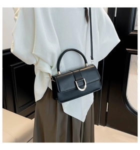 Detail showing classic black crossbody bag worn by model with silver U-shaped metal buckle