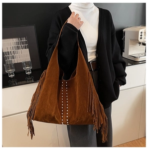 Detail of a large brown suede hobo bag with fringe and rivets in a lifestyle setting