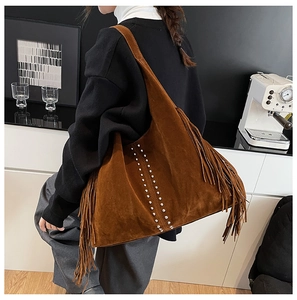 Close-up of brown suede hobo bag featuring decorative long tassels and silver metal rivets