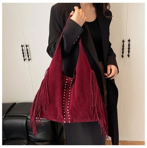 Detail view of burgundy suede hobo bag featuring side tassels and silver stud accents