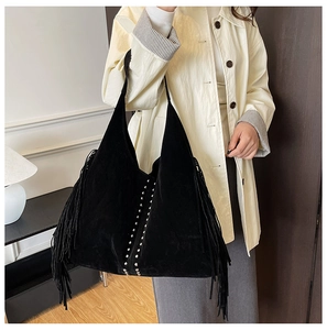 Detailed shot of black suede tote bag with fringe tassels and metallic silver studs