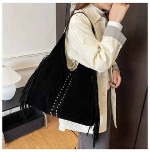 Detail of a large black suede hobo bag with tassel accents and silver rivet decorations