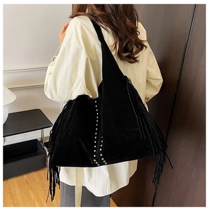 Close-up of black fringe tote bag with silver studs and matte suede texture details