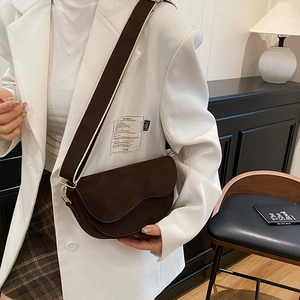 Sacoche selle en daim marron foncé avec rabat ondulé et large bandoulière sur mannequin