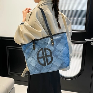 Blue denim patchwork tote bag with geometric stitching and black leather straps