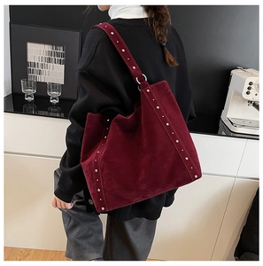 Détail du sac cabas en daim bordeaux avec rivets argentés et anneaux métalliques élégants