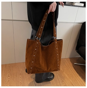 Détail d'un grand sac cabas en daim marron avec rivets argentés décoratifs sur le côté