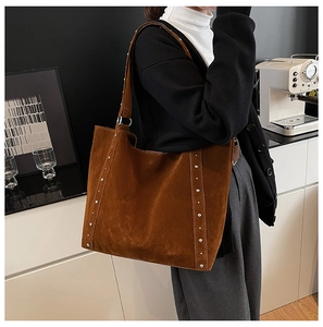 Détail des rivets argentés sur un grand sac cabas en daim marron foncé texturé