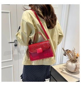 Model view of a red crocodile embossed handbag with top handle and crossbody strap
