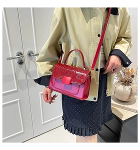 Detail of red crossbody bag featuring crocodile texture flap and magnetic square buckle