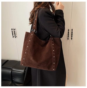 Détail du sac cabas en daim marron avec rivets argentés et surpiqûres de qualité