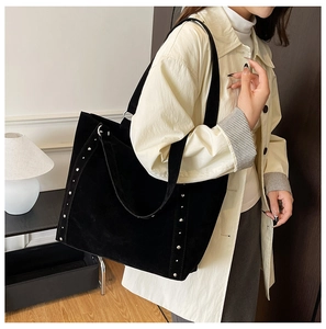 Détail du sac cabas en daim noir avec rivets métalliques et large bandoulière
