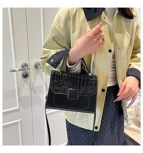 Detail of crocodile embossed flap and square buckle on black minimalist crossbody bag