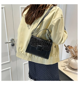 Close-up of black crossbody bag featuring elegant crocodile pattern flap and smooth leather
