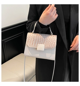 Detail of luxury crocodile pattern flap and square buckle on cream crossbody bag