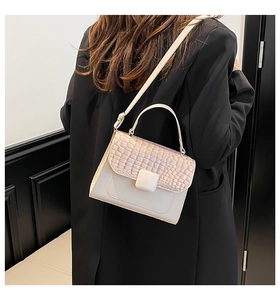 Detail of elegant crocodile textured flap and smooth finish on woman's crossbody bag