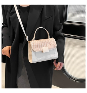 Detail shot of the pink croc-embossed flap and beige smooth leather on the crossbody bag