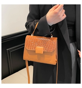 Detail of orange faux leather handbag showing crocodile texture and top handle