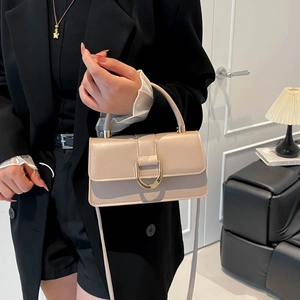 Minimalist beige crossbody box bag with gold metal buckle shown on person