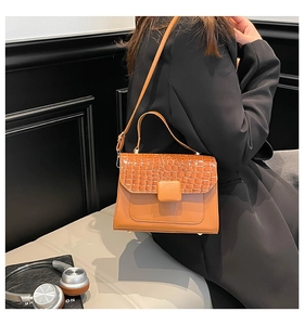 Detail of orange crocodile pattern texture and square buckle on the leather handbag