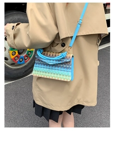 Detail of colorful woven handbag featuring a blue twisted handle and gradient wave pattern