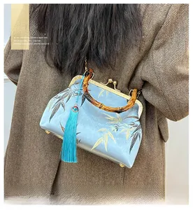Detail of light blue satin bag with bamboo handle and elegant bamboo leaf embroidery