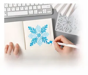 Detail view of using snowflake PET stencil templates for DIY journaling with blue marker