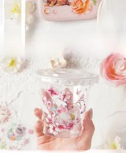 Detail of pink floral and cat stickers applied on a clear plastic cup surface