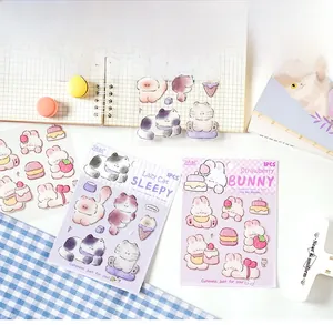 Detail showing 3D cartoon cat and rabbit stickers on a notebook with stationery